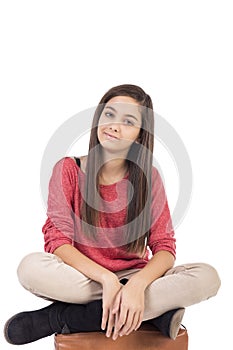 Smiling teenage girl sitting on with legs crossed