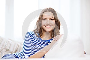 Smiling teenage girl sitting on sofa at home