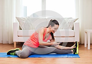 Smiling teenage girl streching on floor at home