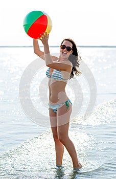 Smiling teenage girl sunglasses with ball on beach