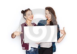 Smiling teenage girls holding white blank board