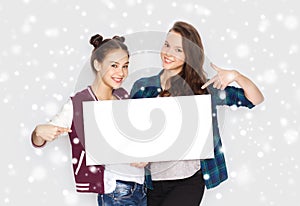 Smiling teenage girls holding white blank board