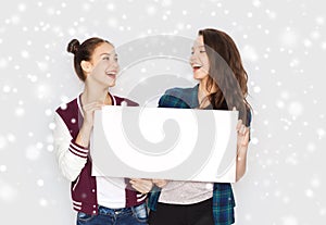 Smiling teenage girls holding white blank board