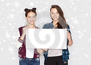 Smiling teenage girls holding white blank board