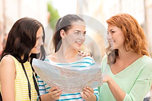 Smiling teenage girls with map and camera