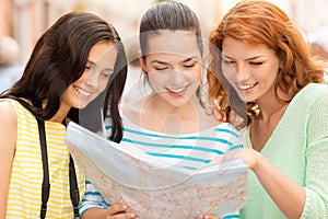 Smiling teenage girls with map and camera