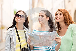 Smiling teenage girls with map and camera