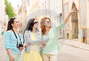 Smiling teenage girls with map and camera