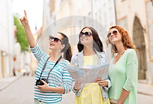 Smiling teenage girls with map and camera