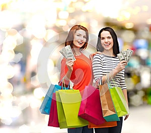 Smiling teenage girls with shopping bags and money