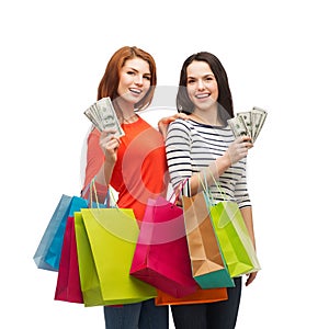 Smiling teenage girls with shopping bags and money