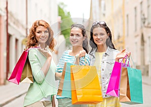 Smiling teenage girls with shopping bags on street
