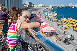 Smiling teenage student girl standing on the embankment near the