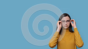 A smiling teenage student girl taking off or putting on glasses. Girl sees better as trying new prescribed glasses. photo