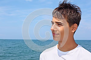 Smiling teenager boy against sea, Looking afar