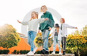 Smiling teenager boy and a laughing sisters girls kids walking in row in the autumnal sunny city park.Careless young teenhood time