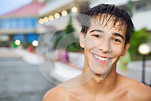 Smiling teenager boy standing on resort in evening photo