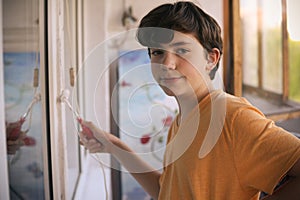 Smiling teenager boy with white paint roller and dirty face make repaint