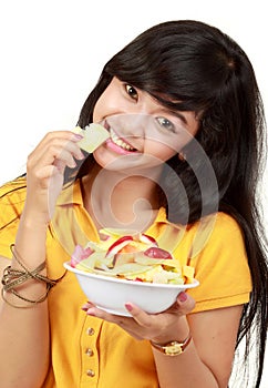 Smiling teenager eating a bowl of cut fruits