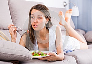 Smiling teenager is enjoying tasty green salad