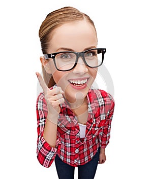 Smiling teenager in eyeglasses with finger up