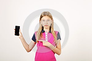 Smiling teenager girl in casual outfit posing with mobile phone, showing emotions, making funny faces. Isolated white background.