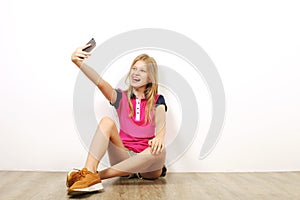 Smiling teenager girl in casual outfit posing with mobile phone, showing emotions, making funny faces. Isolated white background.