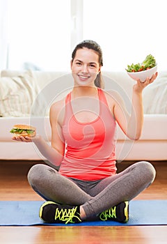 Smiling teenager with green salad and hamburger