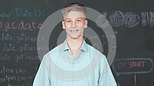 Smiling teenager looking at camera while standing at blackboard. Edification