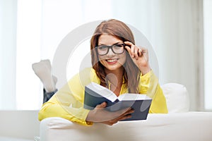 Smiling teenager reading book and sitting on couch