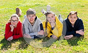 Smiling teenages lying on green grass