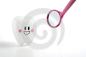 Smiling teeth toy emotion with dental mirror on white background