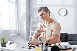 Smiling teleworker looking at laptop and photo