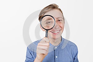 Smiling tennager with magnifying glass on white background. Curious Teenager with Magnifying Glass Isolated on the White