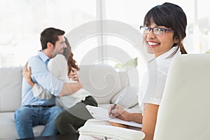 Smiling therapist with patients hugging behind her