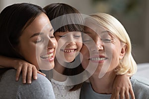 Smiling three generations of women hug and cuddle