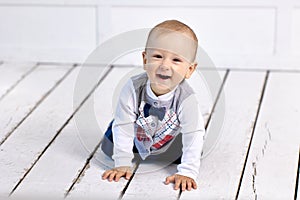 Smiling toddler crawls on flor in lounge.