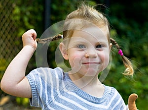 Smiling toddler little blond girl with plaits close up photo