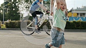 Smiling toddler playing in amusement park. Cute kid throwing frisbee outside