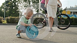 Smiling toddler playing in amusement park. Cute kid throwing frisbee outside