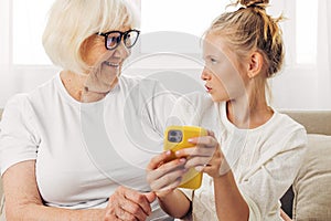 Smiling togetherness granddaughter phone education selfie child sofa family bonding hugging grandmother