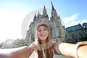 Smiling tourist girl takes self portrait in front of Salford Cathedral, Manchester, England photo