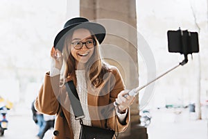 Smiling tourist girl taking photo selfie on smartphone mobile. Blogger hipster travels in Barcelona. Holiday concept in street