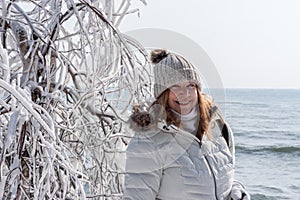 smiling tourist posing next to ice covered tree branches at Cave Point Park, Door County, Wisconsin