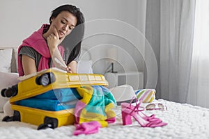 Smiling tourist woman packing suitcase to vacation writing paper list getting ready to travel trip