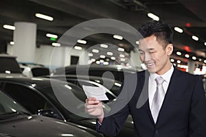 Smiling Traveler looking at ticket in airport parking lot