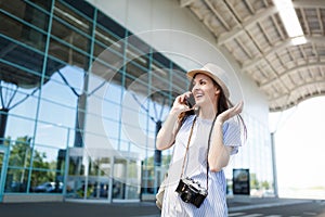 Smiling traveler tourist woman with retro vintage photo camera talk on mobile phone calling friend, booking taxi, hotel