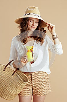 smiling trendy female in blouse and shorts isolated on beige