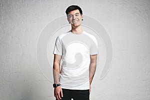 Smiling trendy guy wearing blank white t-shirt, horizontal studio portrait photo