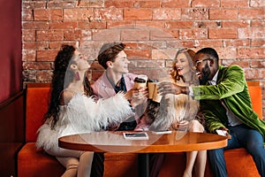 smiling trendy multiethnic young friends drinking coffee from